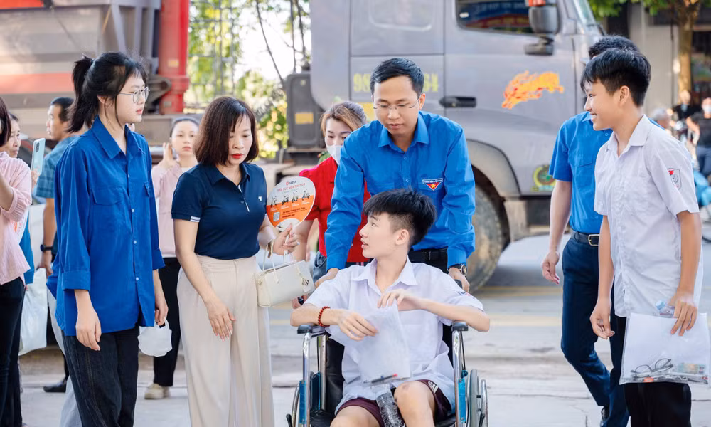 Tình nguyện viên ở Trường THPT Việt Yên số 2 hỗ trợ thí sinh ngồi xe lăn vào phòng thi.