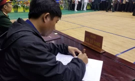 Người dự lễ viếng ghi sổ tang trong buổi tiễn đưa 22 liệt sĩ về nơi an nghỉ cuối cùng.