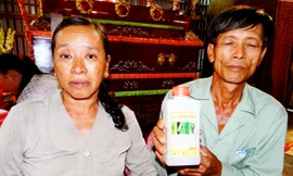 Vợ chồng ông Nguyễn Văn Tổng bên chai thuốc trừ sâu mà Kiệt dùng để tự tử