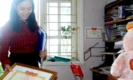 Tay phải cầm tấm bằng khen chống tiêu cực, tai trái chị "Nguyệt Hoài Đức" ôm hàng tệp những nội dung tin nhắn khủng bố, đe dọa trả thù. Phía sau tấm bằng khen chống tiêu cực