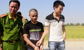 Hung thủ Nguyễn Văn Hải (áo đen) bị cảnh sát áp giải về nơi gây án tìm hung khí chiều 2/6. Ảnh: Lê Hoàng