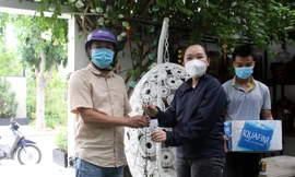 Chậu lan rừng phi điệp được Thảo (áo đen) bán cho khách hàng với giá... 2 thùng nước lọc. Toàn bộ số nhu yếu phẩm này sẽ được hỗ trợ cho các chốt kiểm dịch và khu phong tỏa. Ảnh: Giang Thanh