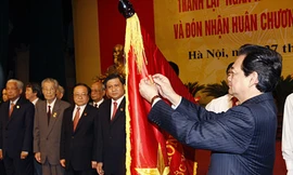 Thủ tướng Nguyễn Tấn Dũng gắn Huân chương Hồ Chí Minh lên lá cờ truyền thống của Ngân hàng Nhà nước Việt Nam Ảnh: TTXVN