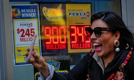 Một phụ nữ đi qua bảng hiệu thông báo giải độc đắc của Mega Millions và Powerball tại văn phòng xổ số bang New York hôm 17/10. Ảnh: Reuters