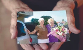 Cụ Disbrow (phải) khoe bức ảnh chụp cùng con gái Betty Jane ngày đoàn tụ. Ảnh: AP