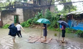 Chủ tịch phường đứng trên bè cho người kéo qua vùng nước ngập