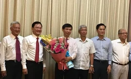 Phó Chủ tịch UBND TPHCM Võ Văn Hoan (thứ ba từ phải qua) trao quyết định và tặng hoa chúc mừng ông Nguyễn Văn Tám