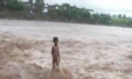 Cậu bé bốn tuổi đứng giữa dòng nước lũ