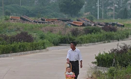 Một ông bố đưa con đi dạo qua đoạn đường có rất nhiều quan tài mới bị đập vỡ ở tỉnh An Huy.