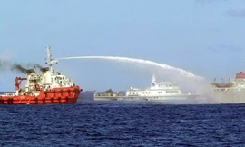Một tàu Trung Quốc (trái) phun vòi rồng vào tàu Việt Nam (phải) trong khi tàu Canh gác bờ biển Trung Quốc chạy ở bên trên Biển Đông ngày hôm qua (7/5). 