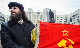 Một người cầm lá cờ Xô Viết đứng trước tượng đài Lenin ở Minsk, Belarus. Ảnh: Reuters. 