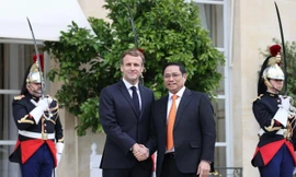 Tổng thống Pháp Emmanuel Macron tiếp đón thân tình Thủ tướng Phạm Minh Chính. Ảnh: TTXVN