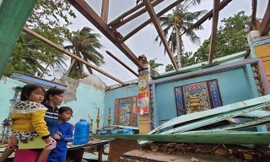 Chị Nguyễn Thị Sương Mai (trú thôn Hòa Lợi, Thị xã Sông Cầu) đứng ôm hai con nhỏ bên căn nhà bị tốc mái, đổ nát do bão...