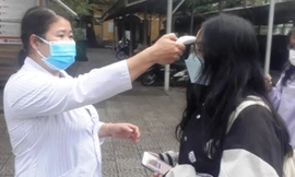 Đo thân nhiệt học sinh trước khi vào lớp tại Trường THPT Nguyễn Trường Tộ, Huế, vào sáng 13/12