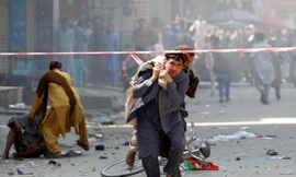 Những người đàn ông giúp đỡ những người bị thương trong vụ đánh bom. Ảnh: Reuters