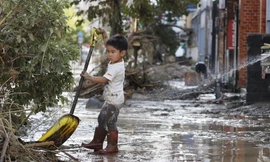 Một đứa trẻ loại bỏ bùn trên một con phố ở Hitoyoshi, tỉnh Kumamoto, phía tây nam Nhật Bản, sau khi sông Kuma tràn qua sau cơn mưa xối xả. Ảnh: Kyodo