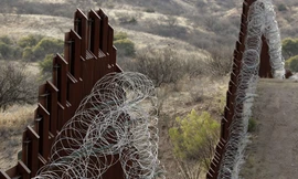 Một bức tường biên giới phủ đầy dây thép gai. Ảnh: AP