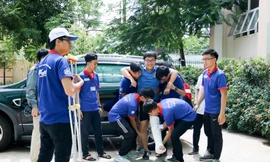 Thí sinh Nguyễn Hoàng Quốc Bảo, THPT Nguyễn Hiền (Q.11, TP.HCM), được các sinh viên tình nguyện đưa lên phòng thi. Ảnh: Trọng Nhân