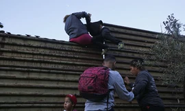 Những người di cư nhau vượt qua bức tường biên giới Mỹ từ Mexico. Ảnh: AP