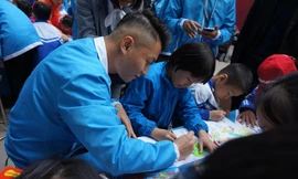 Một đại biểu thanh niên Việt Nam hướng dẫn trẻ khuyết tật tại trường Chuyên biệt Bình Minh, Đông Anh vẽ tranh. Ảnh: Thanh Huyền