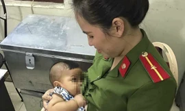 Bé trai đang được cán bộ công an phường chăm sóc.