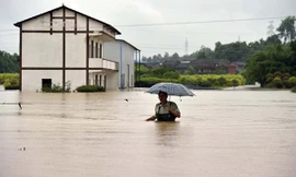 Một người đàn ông cầm ô lội nước ở Trùng Khánh hôm 30/6