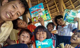 Tác giả và các em nhỏ vùng biên giới thích thú với những cuốn truyện tranh lần đầu biết đến. Ảnh: Nguyễn Thành