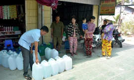 Ông Lê Thành Văn, Trưởng ấp Thanh Tùng (xã Biển Bạch, Thới Bình, Cà Mau) phát nước uống miễn phí từ nhà hảo tâm cho bà con để giải cơn khát. Ảnh: Tân Lộc