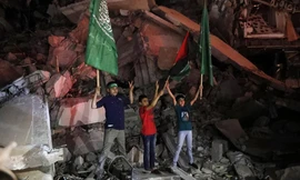 Trẻ em Palestine vẫy cờ Palestine và Hamas khi đang đứng trên đống đổ nát để bày tỏ vui mừng với thỏa thuận ngừng bắn ở Gaza ngày 21/5. Ảnh: AP