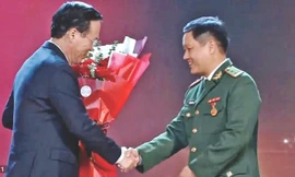 Trung tá Đặng Hùng Cường (bìa phải) nhận hoa chúc mừng mô hình “Lũy tre biên giới Việt” từ Chủ tịch nước Võ Văn Thưởng. Ảnh: Duy Chiến