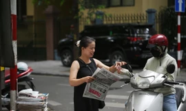 Chị Hường bán báo và tờ lịch thi đấu Euro 2024 cho khách. Ảnh: Trường Phong