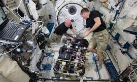 Phi hành gia Kelly (trái) và Watts (phải) đang loại bỏ carbon dioxide trong một thiết bị.