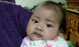 Mặc dù còn ẵm ngửa trên tay nhưng con chị Hương đã biết nói. Ảnh infonet.