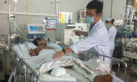 Bác sĩ Huy đang thăm khám cho anh Tám tại khoa hồi sức cấp cứu Bệnh viện Chợ Rẫy. Ảnh: Quốc Ngọc.