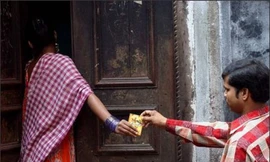 Một gái mại dâm nhận bao cao su miễn phí từ tình nguyện viên tại phố đèn đỏ ở thành phố Calcutta, bang Tây Bengal. Ảnh: AP.