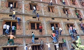 Phụ huynh và người thân thí sinh bất chấp nguy hiểm để leo lên tầng cao ném tài liệu cho con em mình tại một điểm thi ở quận Vaishali, bang Bihar. Ảnh: Hindustan Times.