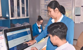 Nhân viên Công ty Điện lực Bình Thuận hướng dẫn khách hàng thao tác thanh toán tiền điện trực tuyến Ảnh: Văn Hơn 