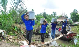 Các sinh viên tình nguyện khuân cát, đá từ dưới ghe lên bờ làm đường Ảnh: Hòa Hội