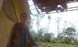 Bà Trần Thị Rê bên mảng tường còn sót lại với những chân nhang còn nguyên lành ảnh: Tr.T 