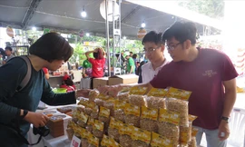 Chàng trai trẻ Tô Nhựt Điền (bên phải) giới thiệu bánh tráng kẹo cho khách hàng Ảnh: U.P 