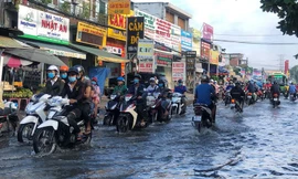 Người dân lội bì bõm giữa dòng nước ngập do trời mưa