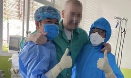 Bệnh nhân 91 tập đi với sự hỗ trợ của nhân viên y tế (ảnh: Lê Nguyễn)