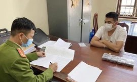 Đối tượng Hoàng Văn Tùng (bìa phải) khai nhận hành vi sản xuất đạn tại cơ quan công an -Ảnh: TL