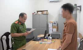 Ông L.V.Q (bìa phải) nghe quyết định khởi tố bị can, khởi tố vụ án trốn thuế -Ảnh: TL