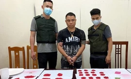 Đối tượng Mạnh (giữa) cùng tang vật bị bắt giữ -Ảnh: A. Khoa