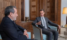 Các tay súng nổi dậy đi qua chiếc xe bọc thép của quân đội Syria bị bỏ lại trên đường cao tốc ở Khan Sheikhoun, phía tây nam Aleppo, ngày 1/12. (Ảnh: AP)