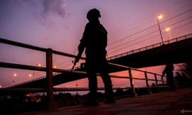 Binh lính đứng gác khi hàng trăm người băng qua sông giữa Myanmar và Thái Lan ở Mae Sot ngày 13/4. (Ảnh: Reuters)