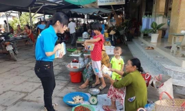 Cán bộ BHXH huyện Trà Cú (Trà Vinh) phát tờ rơi và tuyên truyền chính sách BHXH tự nguyện, BHYT hộ gia đình cho người dân tại các nhóm chợ