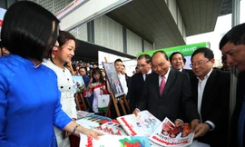 Tổng Biên tập báo Tiền Phong Lê Xuân Sơn giới thiệu các ấn phẩm của báo với Thủ tướng Nguyễn Xuân Phúc tại gian hàng.