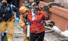 Một người dân được lính cứu hoả đưa ra khỏi toà nhà cháy. (Ảnh: CNN)